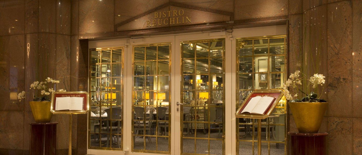 Eleganter Eingang des Bistro Reuchlin mit goldenen Türen, Menükartenständern und dekorativen Pflanzen., © Maritim Hotelgesellschaft mbH