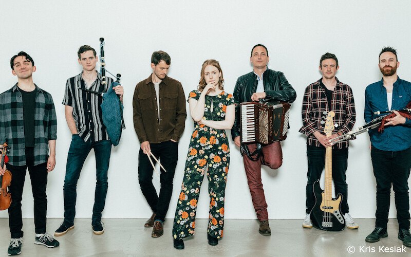 Sieben Musiker posieren mit Instrumenten wie Geige, Dudelsack, Akkordeon und Gitarre vor einem weißen Hintergrund. © Kris Kesiak, © Kultur- und Sportamt Stadt Bietigheim-Bissingen