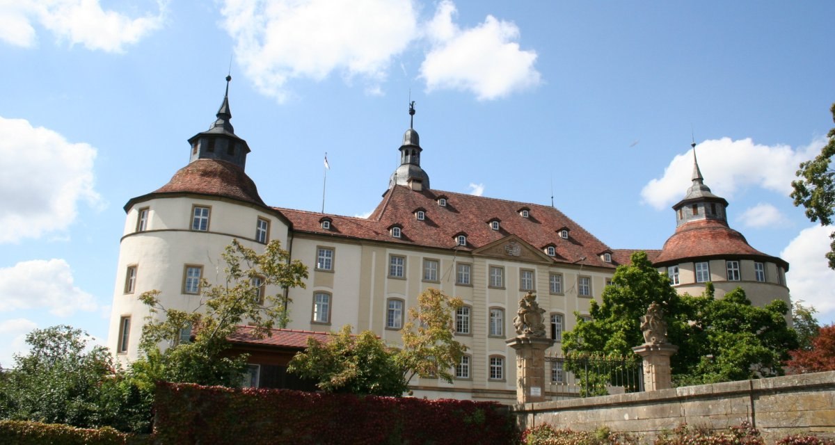 Schloss Langenburg mit zwei markanten Türmen, umgeben von Bäumen und einem Garten. Der Himmel ist blau mit einigen Wolken., © Touristikgemeinschaft Hohenlohe e. V. | Marion Schlund Schloss Langenburg mit zwei markanten Türmen, umgeben von Bäumen und einem Garten. Der Himmel ist blau mit einigen Wolken., © Touristikgemeinschaft Hohenlohe e. V. | Marion Schlund