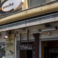 Fassade einer Bar namens La Concha mit Graffiti und Schildern von Erdinger Weißbräu. Die Außenwände sind mit Graffiti verziert., © SMG, Sarah Schmid Fassade einer Bar namens La Concha mit Graffiti und Schildern von Erdinger Weißbräu. Die Außenwände sind mit Graffiti verziert., © SMG, Sarah Schmid