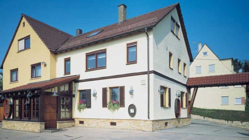 Zweistöckiges Gebäude mit gelber und weißer Fassade, roten Dachziegeln. Ein VdW-Banner steht davor. Klare, blaue Himmel im Hintergrund., © Weinstube Jägerhof Zweistöckiges Gebäude mit gelber und weißer Fassade, roten Dachziegeln. Ein VdW-Banner steht davor. Klare, blaue Himmel im Hintergrund., © Weinstube Jägerhof