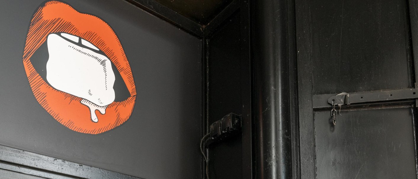 Illustration von roten Lippen mit einem Eiswürfel auf schwarzem Hintergrund. Die Umgebung ist dunkel und industriell gestaltet., © Stuttgart Marketing GmbH, Sarah Schmid