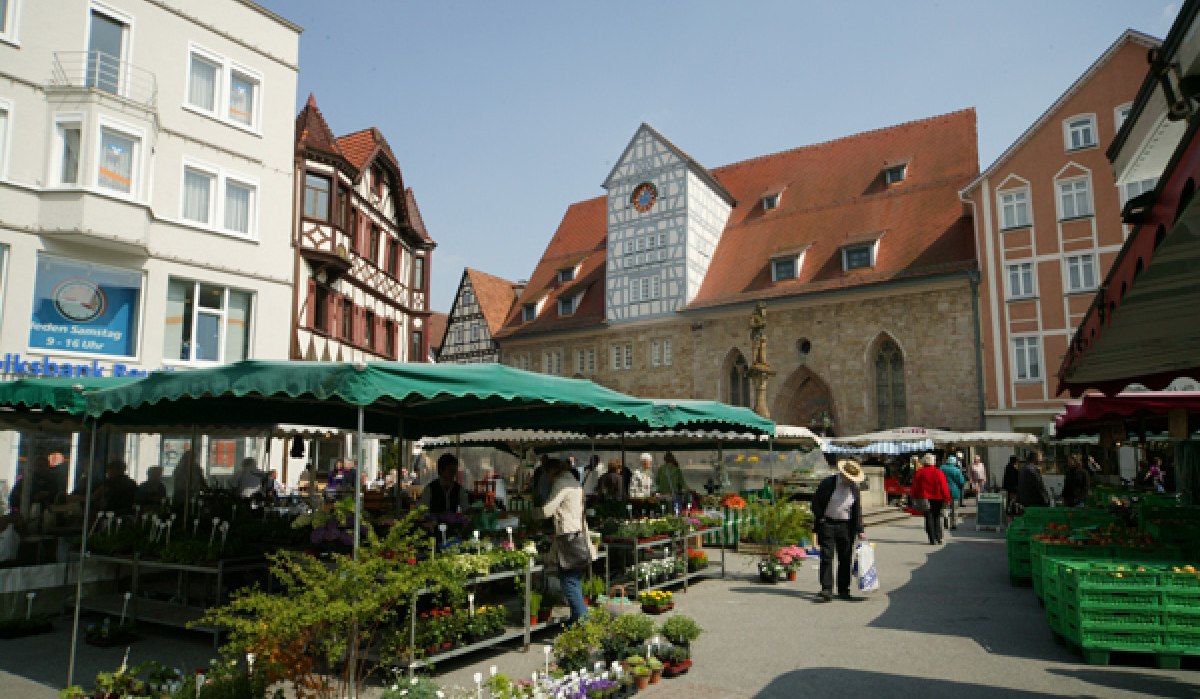 Wochenmarkt in Reutlingen mit Verkaufsständen und Besuchern. Im Hintergrund sind historische Gebäude und der Spitalhof zu sehen., © Sphäre Verlag