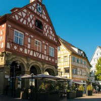 Historisches Fachwerkgebäude am Marktplatz in Waiblingen, umgeben von weiteren Fachwerkhäusern und einem Café im Freien bei sonnigem Wetter., © Stuttgart-Marketing GmbH, Sarah Schmid