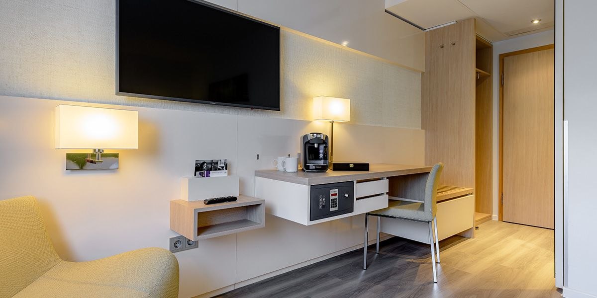 Modernes Hotelzimmer mit Schreibtisch, Fernseher, Kaffeemaschine, Safe und Sitzbereich. Helle Holzmöbel und dezente Beleuchtung schaffen eine gemütliche Atmosphäre., © Mercure Bristol Stuttgart Sindelfingen