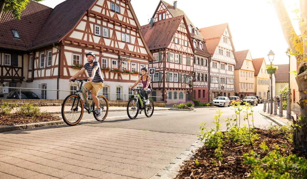 Zwei Radfahrer in der Altstadt von Weil der Stadt, umgeben von malerischen Fachwerkhäusern und sonnigem Wetter., © Stadtmarketing Weil der Stadt Zwei Radfahrer in der Altstadt von Weil der Stadt, umgeben von malerischen Fachwerkhäusern und sonnigem Wetter., © Stadtmarketing Weil der Stadt