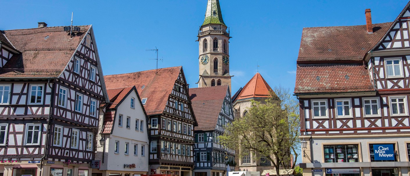 Fachwerkhäuser am Marktplatz in Schorndorf, mit einem Kirchturm im Hintergrund. Menschen spazieren über den Platz bei sonnigem Wetter., © Stuttgart-Marketing GmbH Fachwerkhäuser am Marktplatz in Schorndorf, mit einem Kirchturm im Hintergrund. Menschen spazieren über den Platz bei sonnigem Wetter., © Stuttgart-Marketing GmbH
