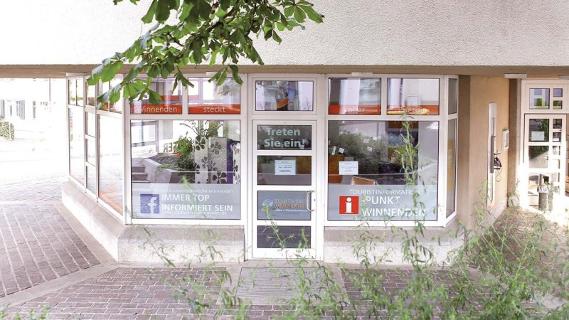 Eingang der Touristinformation in Winnenden mit großen Fenstern, Schildern und Pflanzen im Inneren. Einladende Atmosphäre mit offenen Türen., © Stadt Winnenden