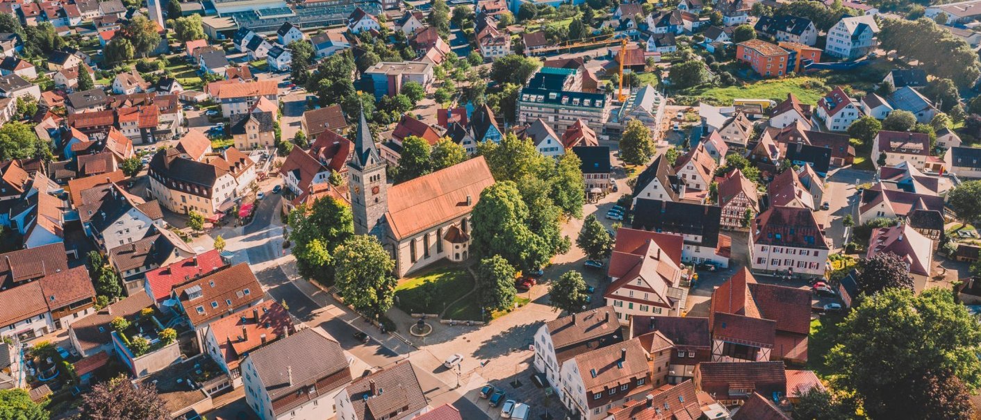 Luftaufnahme einer kleinen Stadt mit einer Kirche im Zentrum, umgeben von Wohnh&auml;usern und gr&uuml;nen B&auml;umen., &copy; Sandra Bihlmaier - Stadt Welzheim