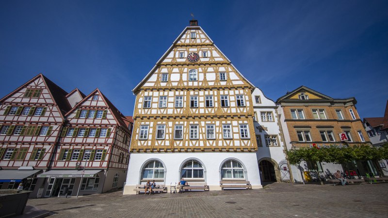 Historische Fachwerkh&auml;user in Leonberg, Deutschland, bei strahlend blauem Himmel. Menschen sitzen auf B&auml;nken vor den Geb&auml;uden., &copy; Achim Mende
