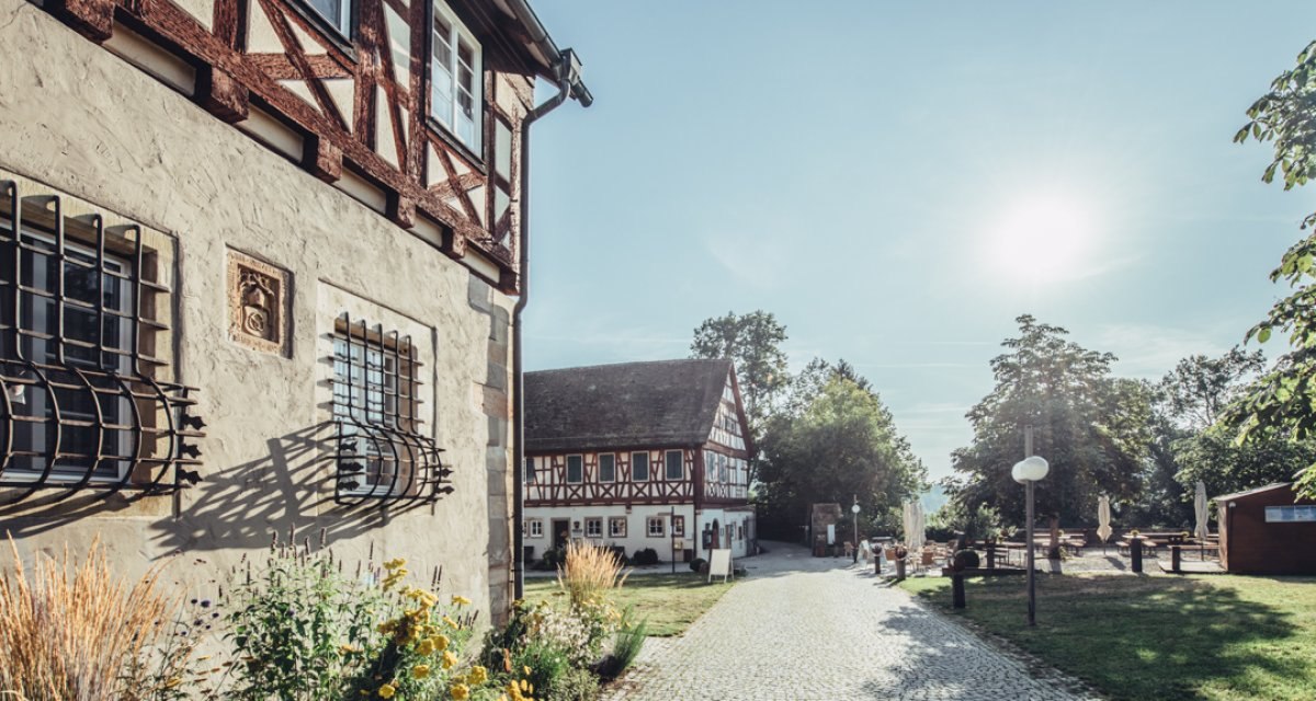 Innenhof des Klosters Lorch mit Fachwerkgebäuden, gepflastertem Weg und blühenden Pflanzen bei sonnigem Wetter., © Tourismus Ostalb Innenhof des Klosters Lorch mit Fachwerkgebäuden, gepflastertem Weg und blühenden Pflanzen bei sonnigem Wetter., © Tourismus Ostalb