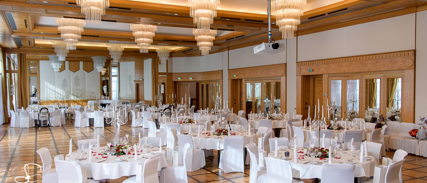 Eleganter Bankettsaal mit runden, weiß gedeckten Tischen, weißen Stühlen und beeindruckenden Kronleuchtern an der Decke., © Pullman Stuttgart Fontana Eleganter Bankettsaal mit runden, weiß gedeckten Tischen, weißen Stühlen und beeindruckenden Kronleuchtern an der Decke., © Pullman Stuttgart Fontana