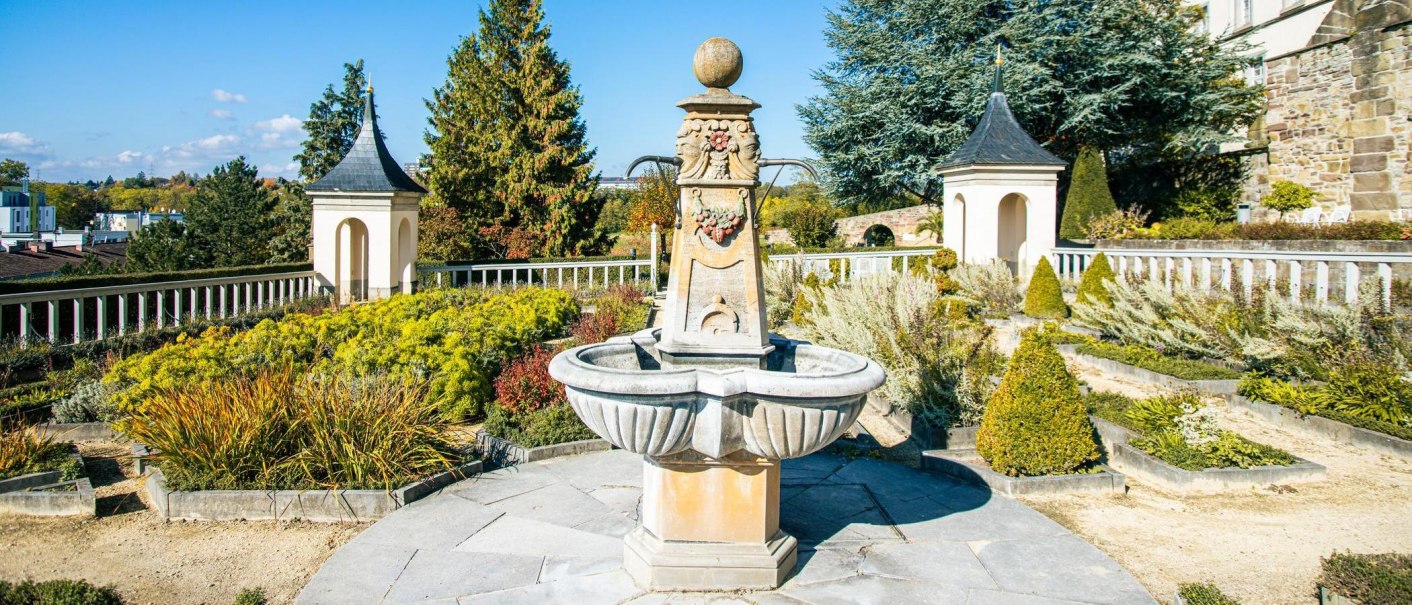 Ein Brunnen im Pomeranzengarten von Schloss Leonberg, umgeben von Pflanzen und Bäumen. Der Himmel ist klar und blau., © Stuttgart-Marketing GmbH, Sarah Schmid Ein Brunnen im Pomeranzengarten von Schloss Leonberg, umgeben von Pflanzen und Bäumen. Der Himmel ist klar und blau., © Stuttgart-Marketing GmbH, Sarah Schmid