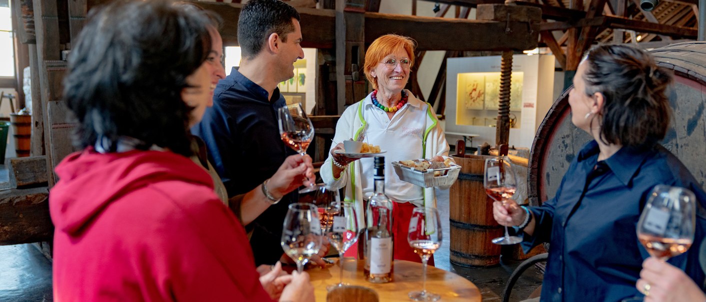 Eine Gruppe von Menschen genie&szlig;t eine Weinprobe im Weinbaumuseum. Eine Frau serviert Snacks, w&auml;hrend die anderen Wein in Gl&auml;sern halten., &copy; Stuttgart-Marketing GmbH, Thomas Niederm&uuml;ller
