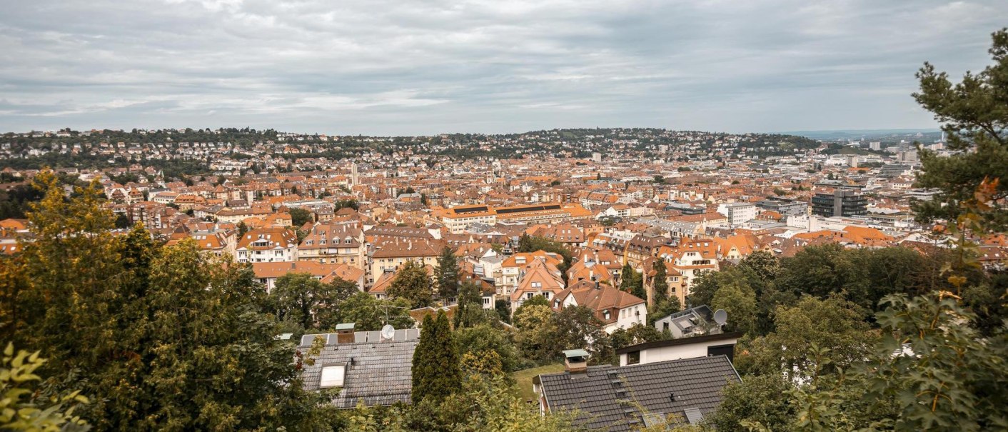 Panoramablick auf Stuttgart von der Hasenbergsteige aus. Die Stadt erstreckt sich mit roten Dächern und grünen Hügeln im Hintergrund., © Stuttgart-Marketing GmbH, Sarah Schmid