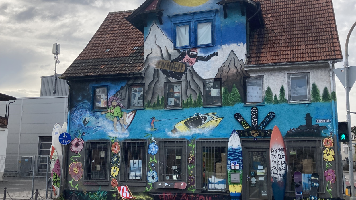 Ein bunt bemaltes Gebäude mit Surfmotiven und Graffiti. Vor dem Eingang stehen Surfboards. Der Himmel ist bewölkt., © L. Besemer Ein bunt bemaltes Gebäude mit Surfmotiven und Graffiti. Vor dem Eingang stehen Surfboards. Der Himmel ist bewölkt., © L. Besemer