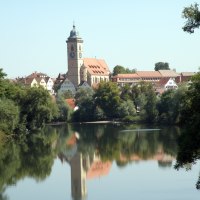 N&uuml;rtingen am Neckar mit einer Kirche im Zentrum, umgeben von B&auml;umen. Die Spiegelung der Stadt ist im ruhigen Wasser sichtbar., &copy; Stadt N&uuml;rtingen