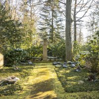 Ein ruhiger Friedhof mit einem großen Kreuz in der Mitte, umgeben von Bäumen und grüner Vegetation. Sonnenlicht fällt durch die Blätter., © Stuttgart-Marketing GmbH, Sarah Schmid