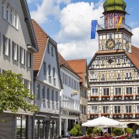 Das Fachwerk-Rathaus von Kirchheim unter Teck mit Uhrturm, umgeben von historischen Gebäuden und einem belebten Platz mit Cafés., © Torsten Wenzler
