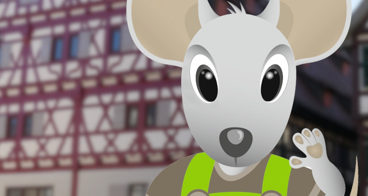 Eine animierte Maus namens Herri in gr&uuml;ner Latzhose steht vor einem Fachwerkgeb&auml;ude. Die Maus winkt freundlich., &copy; Stadt Herrenberg