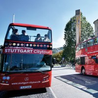 Zwei rote Doppeldeckerbusse der Stuttgart Citytour stehen vor dem Landesmuseum W&uuml;rttemberg. Menschen sitzen auf dem offenen Oberdeck., &copy; Stuttgart-Marketing GmbH, Pierre Polak