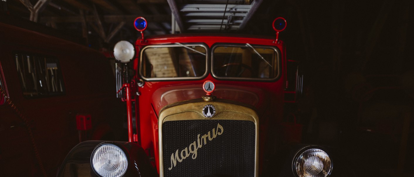 Ein rotes, historisches Feuerwehrfahrzeug der Marke Magirus im Feuerwehrmuseum Schwäbisch Hall, mit blauen Rundlichtern und einem goldenen Kühlergrill., © Nico Kurth Ein rotes, historisches Feuerwehrfahrzeug der Marke Magirus im Feuerwehrmuseum Schwäbisch Hall, mit blauen Rundlichtern und einem goldenen Kühlergrill., © Nico Kurth