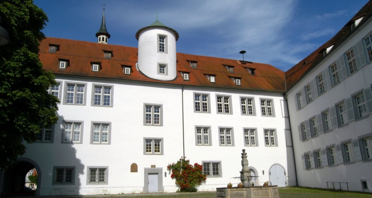 Historischer Innenhof mit wei&szlig;em Geb&auml;ude, rotem Dach und kleinem Turm. Ein Brunnen steht in der Mitte des gepflasterten Platzes., &copy; Natur.Nah. Sch&ouml;nbuch & Heckeng&auml;u