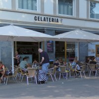 Menschen sitzen unter Sonnenschirmen vor der Gelateria Kaiserbau am Marienplatz. Einige Passanten gehen vorbei., © Stuttgart-Marketing GmbH