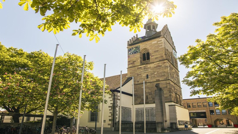 Die Lutherkirche in Fellbach mit ihrem markanten Turm, umgeben von grünen Bäumen und Sonnenschein, bietet einen idyllischen Anblick., © SMG, Sarah Schmid