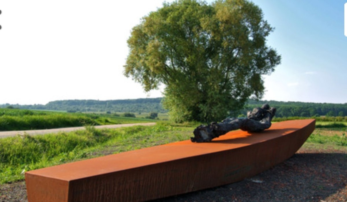 Eine rostfarbene Skulptur auf dem Besinnungsweg Fellbach, umgeben von grüner Landschaft und einem großen Baum im Hintergrund., © www.besinnungsweg-fellbach.de Eine rostfarbene Skulptur auf dem Besinnungsweg Fellbach, umgeben von grüner Landschaft und einem großen Baum im Hintergrund., © www.besinnungsweg-fellbach.de