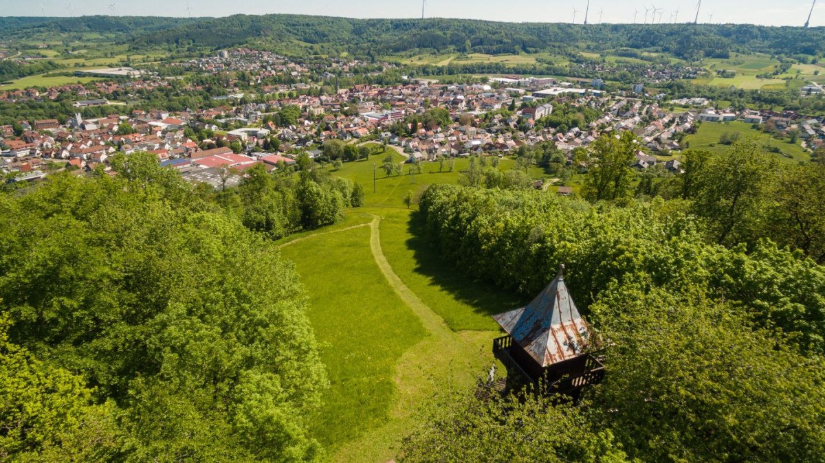 Luftbild des Kernerturms und der Stadt Gaildorf, umgeben von grünen Wäldern und Hügeln. Im Vordergrund ein Weg, im Hintergrund die Stadt und Windräder., © Stadt Gaildorf