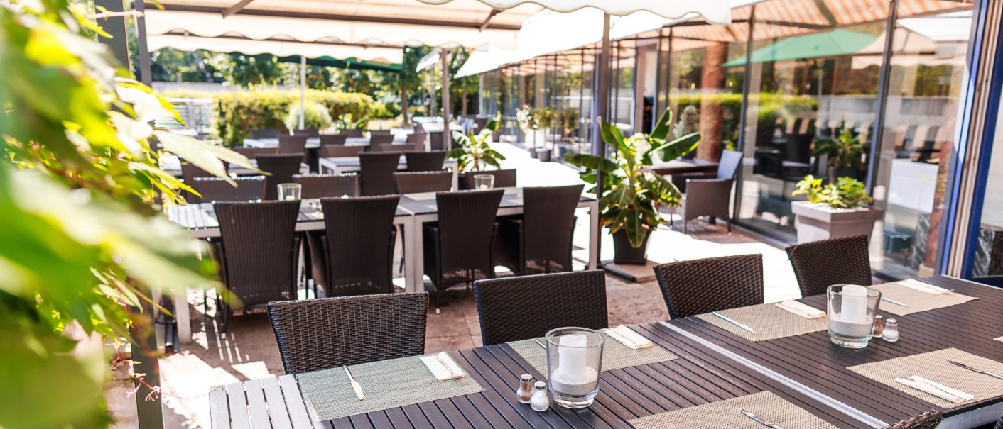 Restaurantterrasse mit gedeckten Tischen und Stühlen unter Sonnenschirmen, umgeben von Pflanzen., © PLAZA Hotelgroup GmbH Restaurantterrasse mit gedeckten Tischen und Stühlen unter Sonnenschirmen, umgeben von Pflanzen., © PLAZA Hotelgroup GmbH