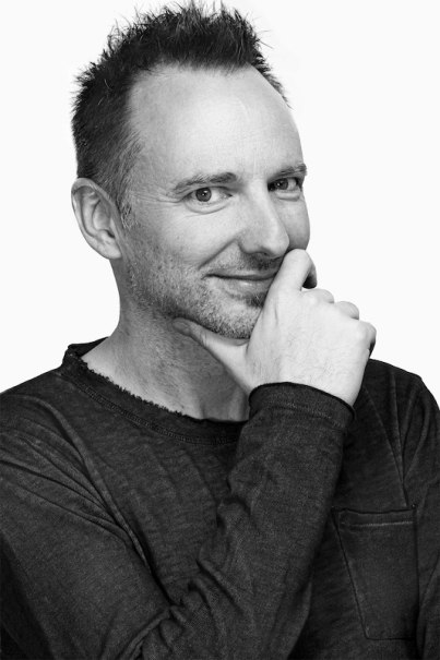 Ein Mann mit kurzem Haar und Bart lächelt in die Kamera und legt nachdenklich seine Hand ans Kinn. Er trägt ein dunkles Oberteil., © Stadtverwaltung Remseck am Neckar