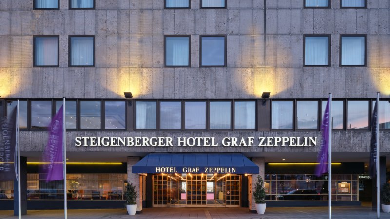 Au&szlig;enansicht des Steigenberger Hotel Graf Zeppelin mit beleuchtetem Eingang und Fahnen., &copy; Steigenberger Graf Zeppelin