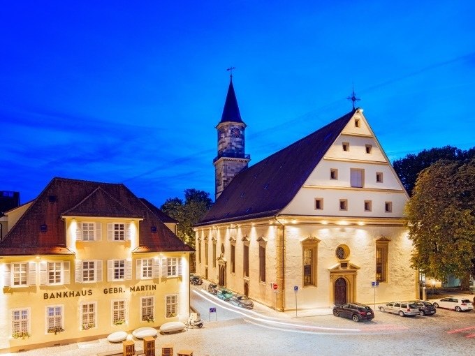 Die Göppinger Stadtkirche bei Nacht, umgeben von beleuchteten Gebäuden und einem klaren blauen Himmel., © Stadt Göppingen Die Göppinger Stadtkirche bei Nacht, umgeben von beleuchteten Gebäuden und einem klaren blauen Himmel., © Stadt Göppingen