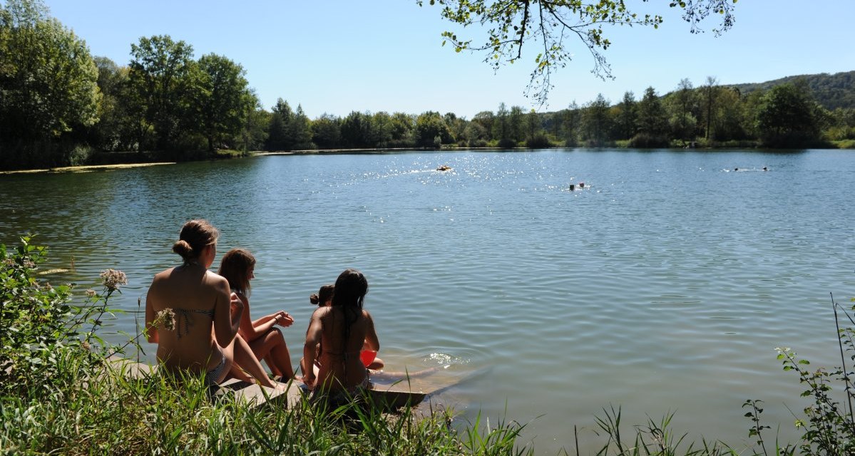 Menschen sitzen am Ufer eines Sees, genießen die Sonne und beobachten Schwimmer im Wasser. Umgeben von grüner Natur und klarem Himmel., © Land der 1000 Hügel - Kraichgau-Stromberg Menschen sitzen am Ufer eines Sees, genießen die Sonne und beobachten Schwimmer im Wasser. Umgeben von grüner Natur und klarem Himmel., © Land der 1000 Hügel - Kraichgau-Stromberg