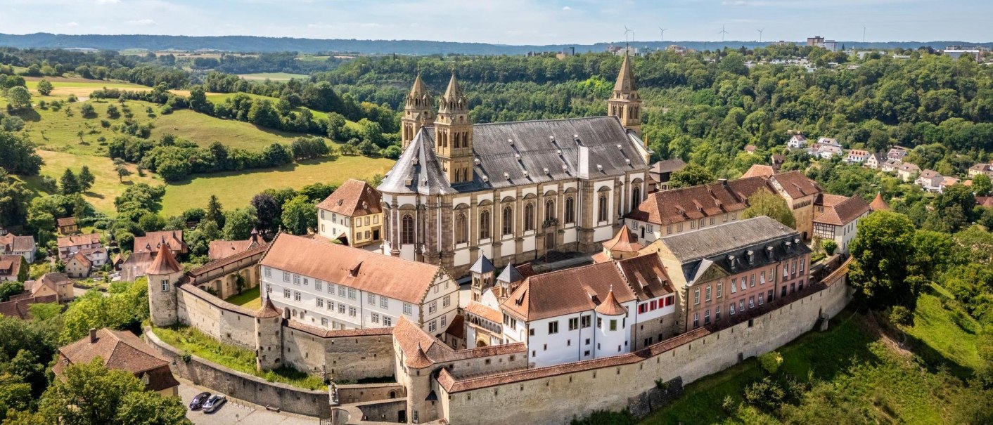 Luftaufnahme der Comburg in Schw&auml;bisch Hall, umgeben von gr&uuml;nen Feldern und W&auml;ldern. Die historische Klosteranlage ist von einer Mauer umgeben., &copy; Stadt Schw&auml;bisch Hall - Michael K&uuml;hneisen