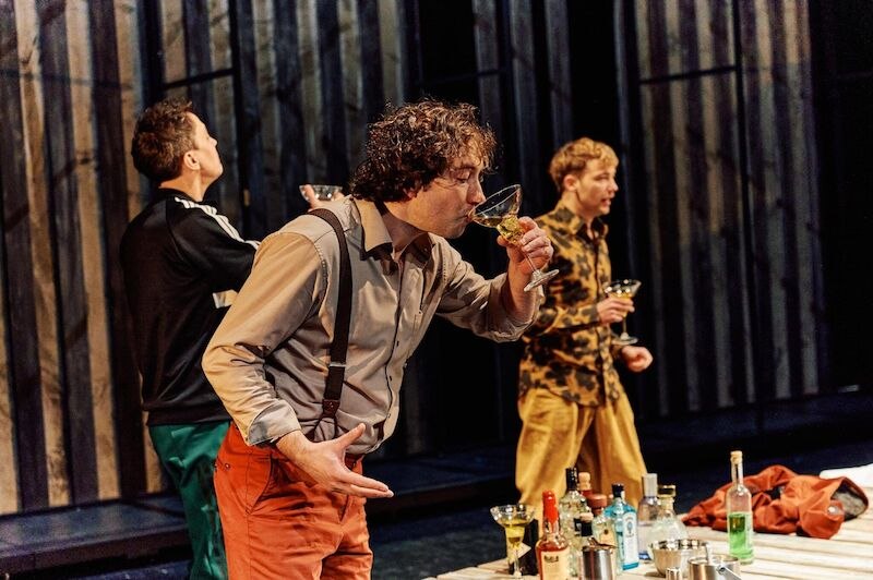 Drei Männer auf einer Bühne trinken Cocktails. Ein Tisch mit verschiedenen Flaschen steht im Vordergrund. Die Szene wirkt lebhaft und dynamisch., © Kulturbüro Schwäbisch Gmünd Drei Männer auf einer Bühne trinken Cocktails. Ein Tisch mit verschiedenen Flaschen steht im Vordergrund. Die Szene wirkt lebhaft und dynamisch., © Kulturbüro Schwäbisch Gmünd