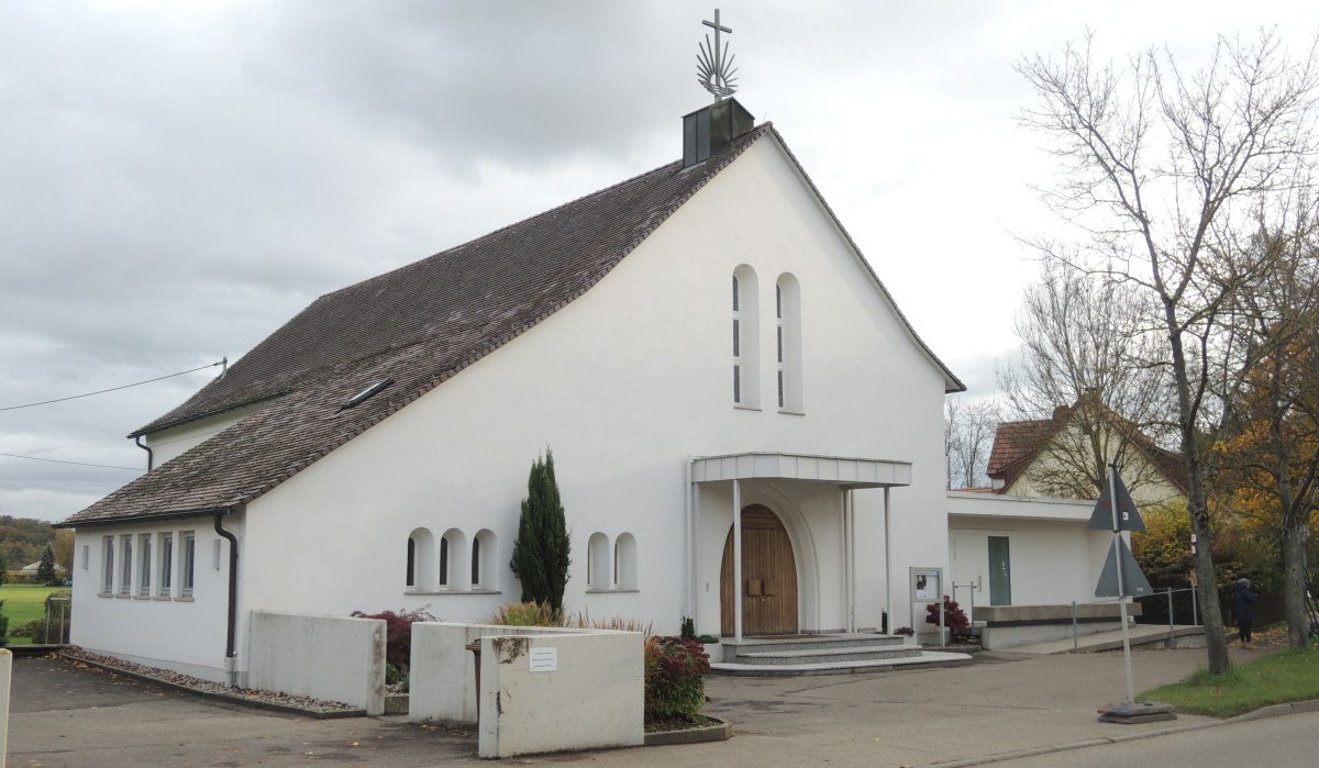 Weiße Kirche mit spitzem Dach und Kreuz, umgeben von Bäumen und Gehweg. Der Himmel ist bewölkt., © Land der 1000 Hügel - Kraichgau-Stromberg Weiße Kirche mit spitzem Dach und Kreuz, umgeben von Bäumen und Gehweg. Der Himmel ist bewölkt., © Land der 1000 Hügel - Kraichgau-Stromberg