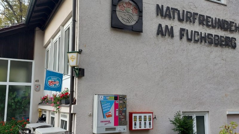 Gebäude mit der Aufschrift 'Naturfreunde am Fuchsberg', Tisch und Stühle draußen, Getränkeautomat an der Wand., © Naturfreunde Sindelfingen Gebäude mit der Aufschrift 'Naturfreunde am Fuchsberg', Tisch und Stühle draußen, Getränkeautomat an der Wand., © Naturfreunde Sindelfingen