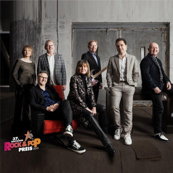 Eine Gruppe von sieben Personen posiert in einem industriellen Raum. Sie tragen elegante Kleidung und wirken entspannt und selbstbewusst., &copy; Mauerwerk GmbH