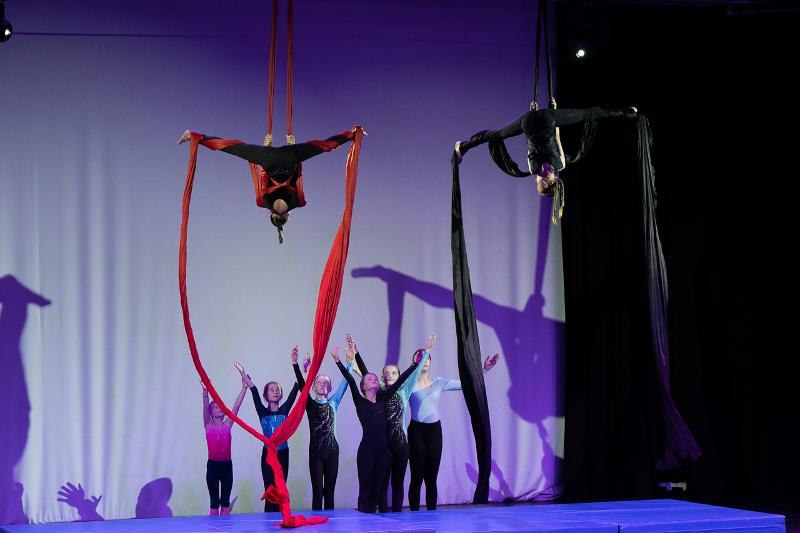 Kinder zeigen Luftakrobatik mit T&uuml;chern auf einer B&uuml;hne. Zwei Akrobaten h&auml;ngen kopf&uuml;ber an roten und schwarzen T&uuml;chern, w&auml;hrend andere Kinder zuschauen., &copy; Kunstschule Labyrinth