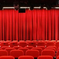 Leerer Theatersaal mit roten St&uuml;hlen und geschlossenem roten Vorhang, Beleuchtung und Lautsprechern an der Decke., &copy; Sabine Haymann