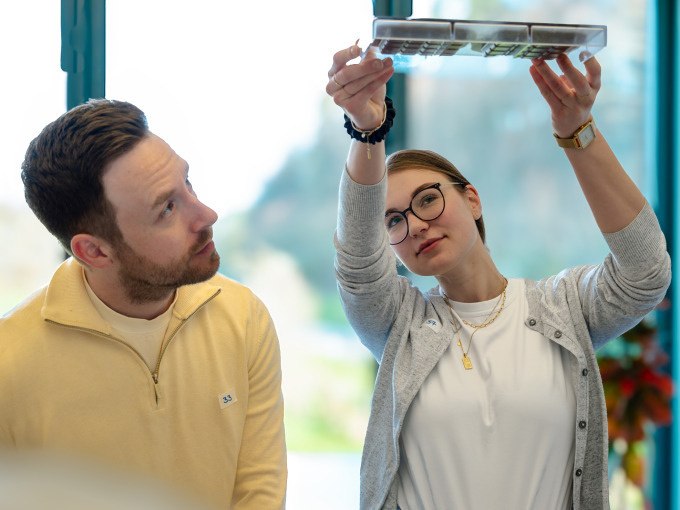 Zwei Personen, eine Frau und ein Mann, betrachten eine Schokoladentafel gegen das Licht. Die Frau h&auml;lt die Tafel hoch, w&auml;hrend der Mann interessiert schaut., &copy; Alfred Ritter GmbH &amp; Co. KG | Waldenbuch
