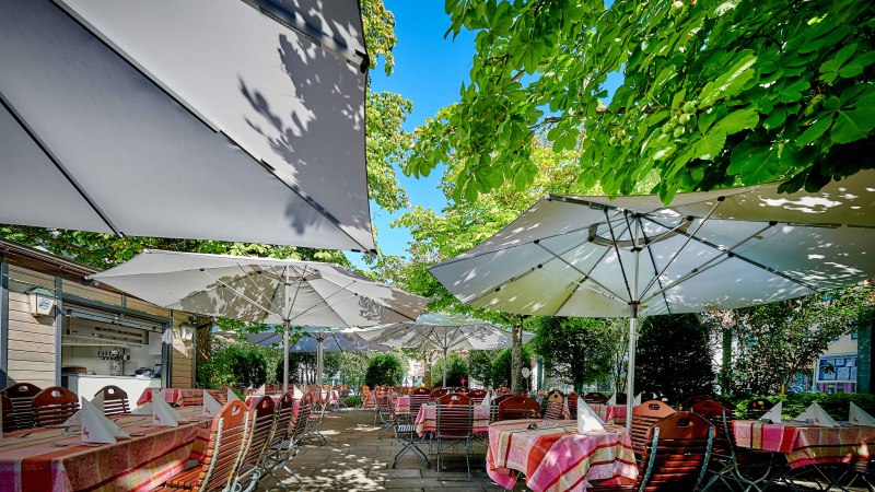 Gartenterrasse mit gedeckten Tischen unter gro&szlig;en Sonnenschirmen, umgeben von &uuml;ppigem Gr&uuml;n und B&auml;umen., &copy; Hotel Gasthof Hasen