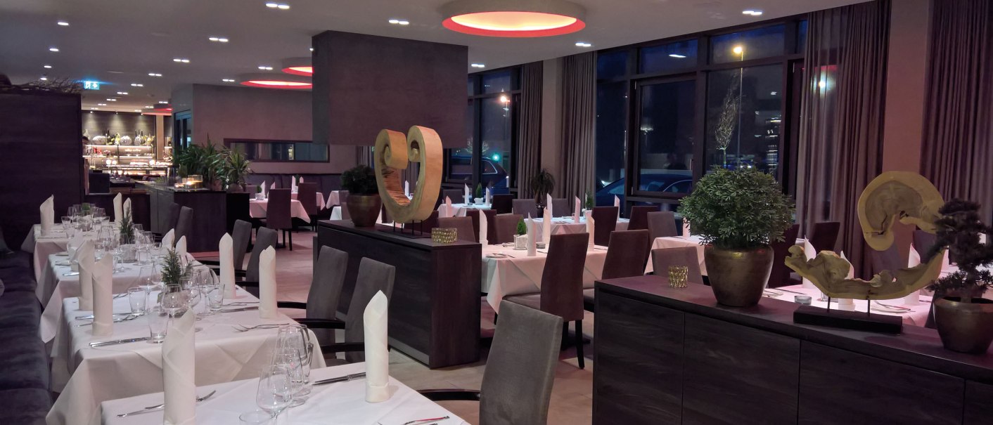 Elegantes Restaurant mit weiß gedeckten Tischen, modernen Skulpturen und gedämpfter Beleuchtung. Große Fenster und stilvolle Einrichtung., © Hotel Eislinger Tor