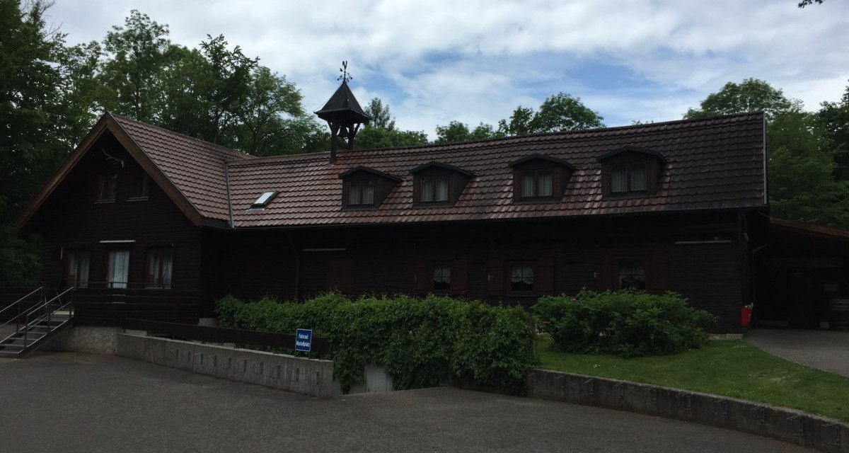 Eine rustikale Holzh&uuml;tte mit Satteldach und kleinem Turm, umgeben von B&auml;umen. Der Vorplatz ist gepflastert und es gibt einen kleinen Garten., &copy; www.pro-cycl.de