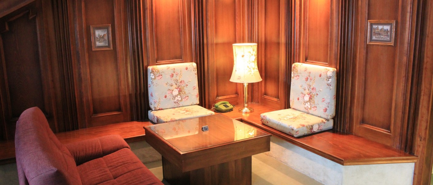 Gem&uuml;tliche Sitzecke mit Holzw&auml;nden, floral gemusterten Kissen, Tisch und Lampe. Ein Telefon steht auf dem Tisch., &copy; Hotel Spahr
