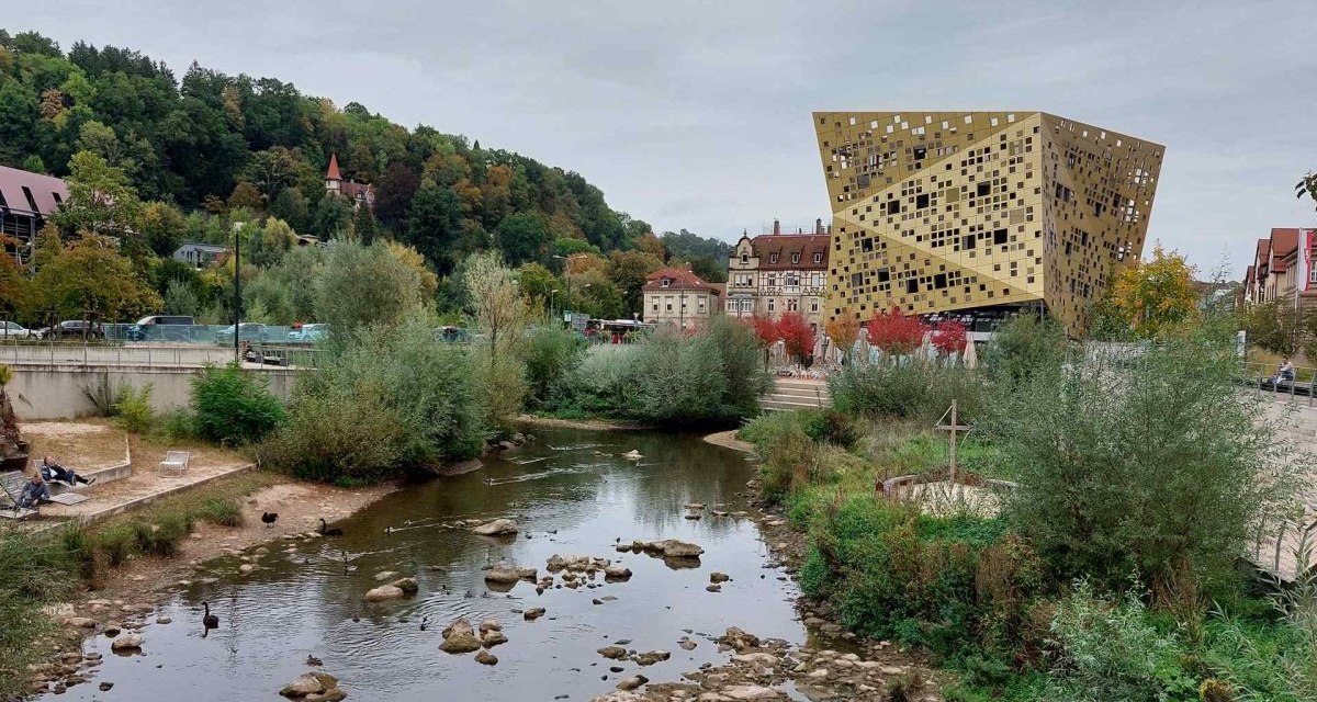 Goldenes Gebäude in Schwäbisch Gmünd neben einem Fluss, umgeben von Bäumen und alten Häusern., © Remstal Tourismus e.V. I Architekt: isin Architekten Goldenes Gebäude in Schwäbisch Gmünd neben einem Fluss, umgeben von Bäumen und alten Häusern., © Remstal Tourismus e.V. I Architekt: isin Architekten