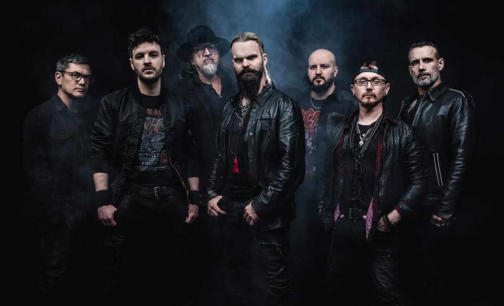 Sieben Männer in schwarzer Kleidung posieren vor einem dunklen, nebligen Hintergrund. Sie tragen Lederjacken und haben ernste Gesichtsausdrücke., © Music Circus Concertbüro GmbH & Co. KG